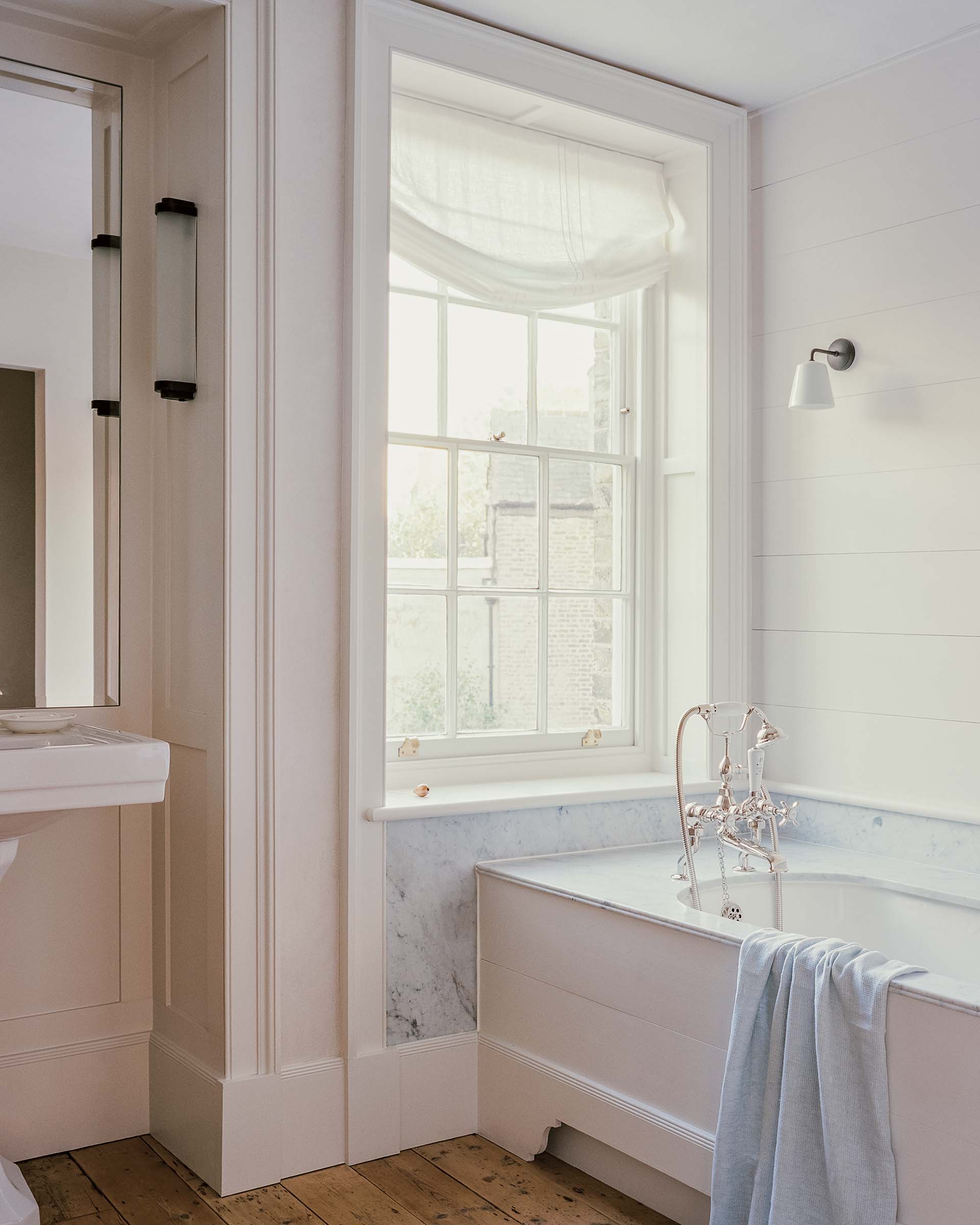 traditional bathroom interior design in a Georgian cottage in Hampstead, with window panelling and marble bath